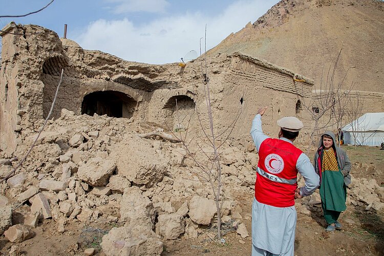 Helfer des Afghanischen Roten Halbmondes spricht mit einem Jungen 