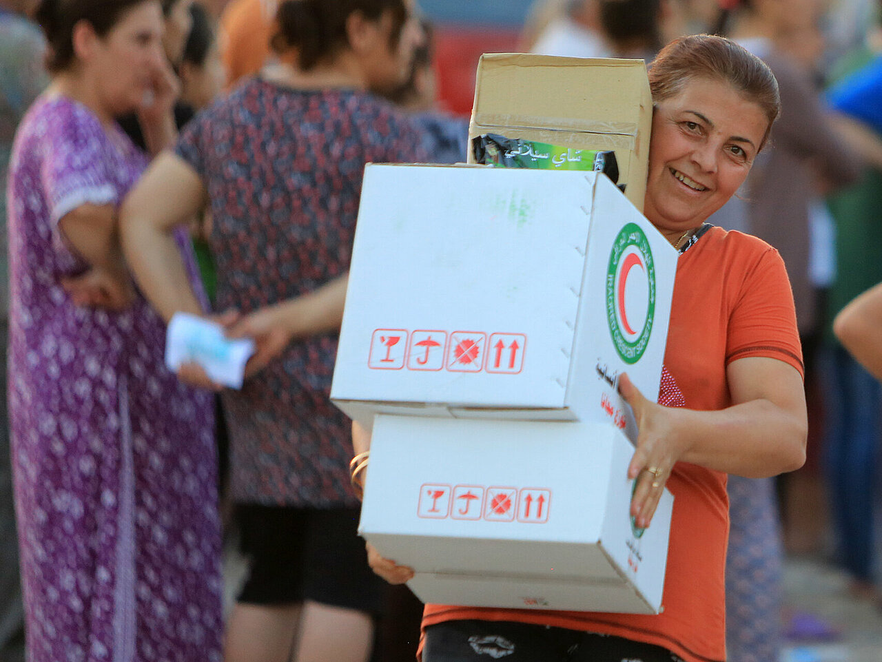 Ältere Frau im Irak trägt Hilfspakete