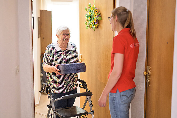 Essen auf Rädern DRKlerin übergibt Box an Seniorin