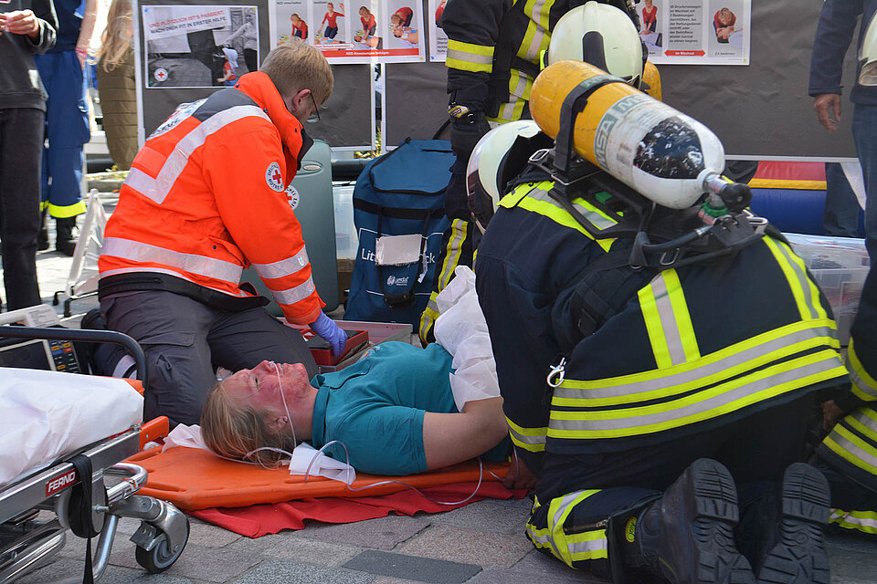 Ehrenamtlicher des DRK und Feuerwehr bei der Ersten Hilfe einer Verletzten