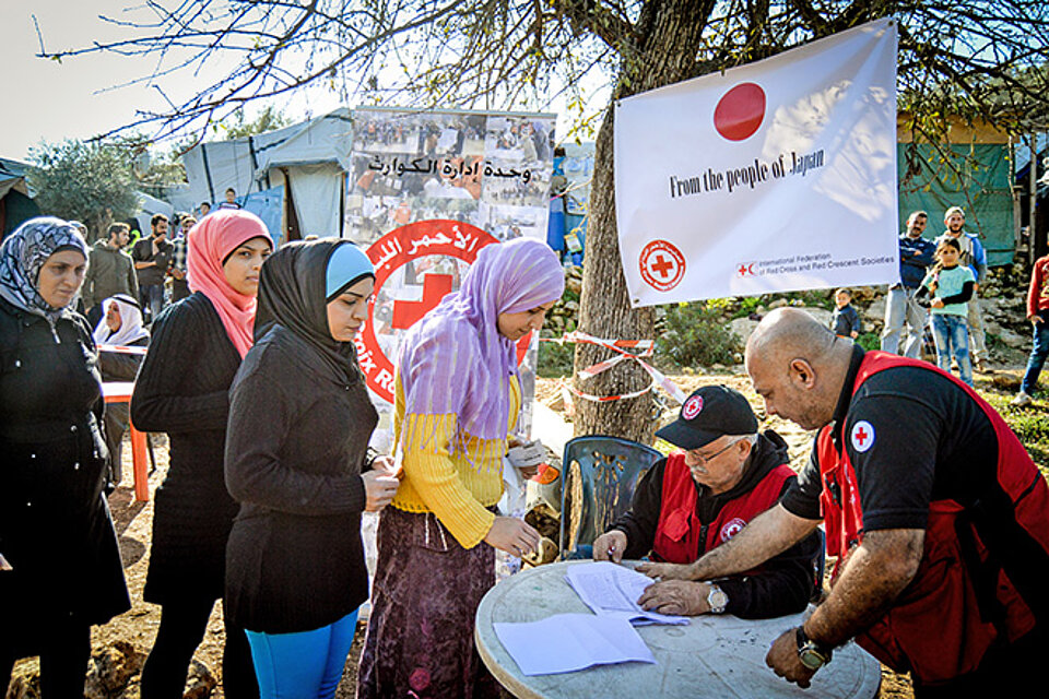Frauen stehen an bei Humanitärer Geldleistungsverteilung vom Roten Halbmond