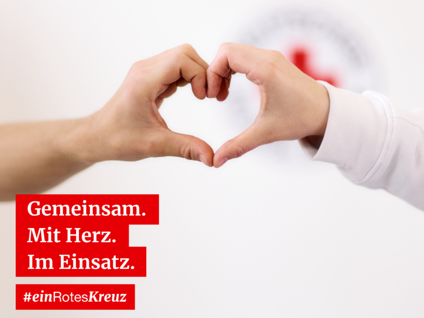 Zwei Hände formen ein Herz, mit unscharfem Logo des Deutschen Roten Kreuzes im Hintergrund. Text: "8. Mai Weltrotkreuztag. Gemeinsam. Mit Herz. Im Einsatz. #einRotesKreuz."