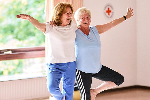 Zwei Frauen stehen mit angewinkeltem Bein