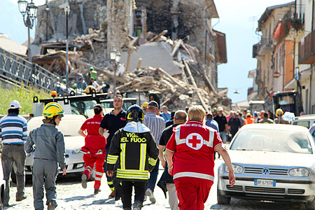 Rotkreuz-Helfer vor Trümmern nach Erdbeben