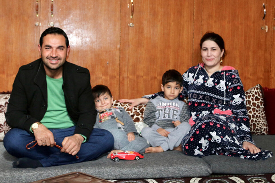 Foto: Ein syrisches Ehepaar und ihre zwei Kinder zwischen ihnen sitzen auf einer Matte