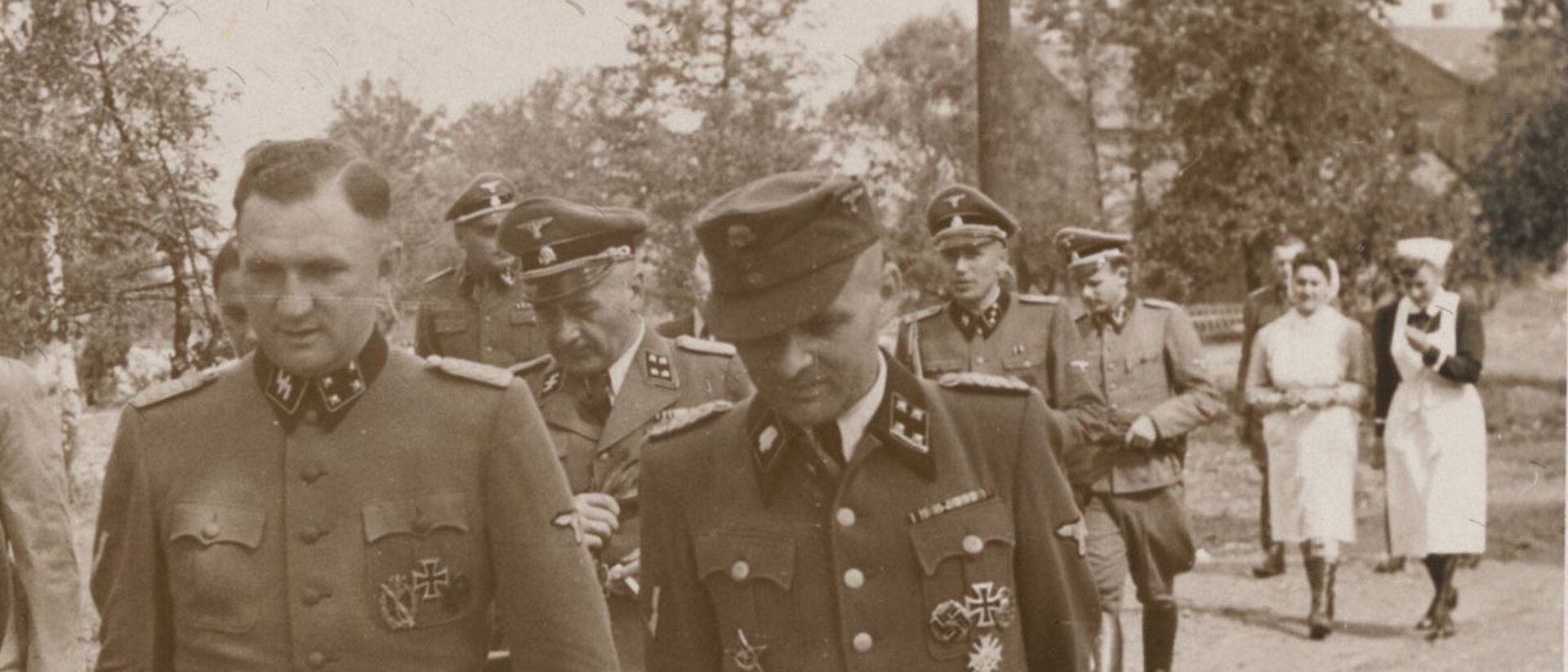 Rotkreuzschwester und NS-Schwester hinter SS-Männern