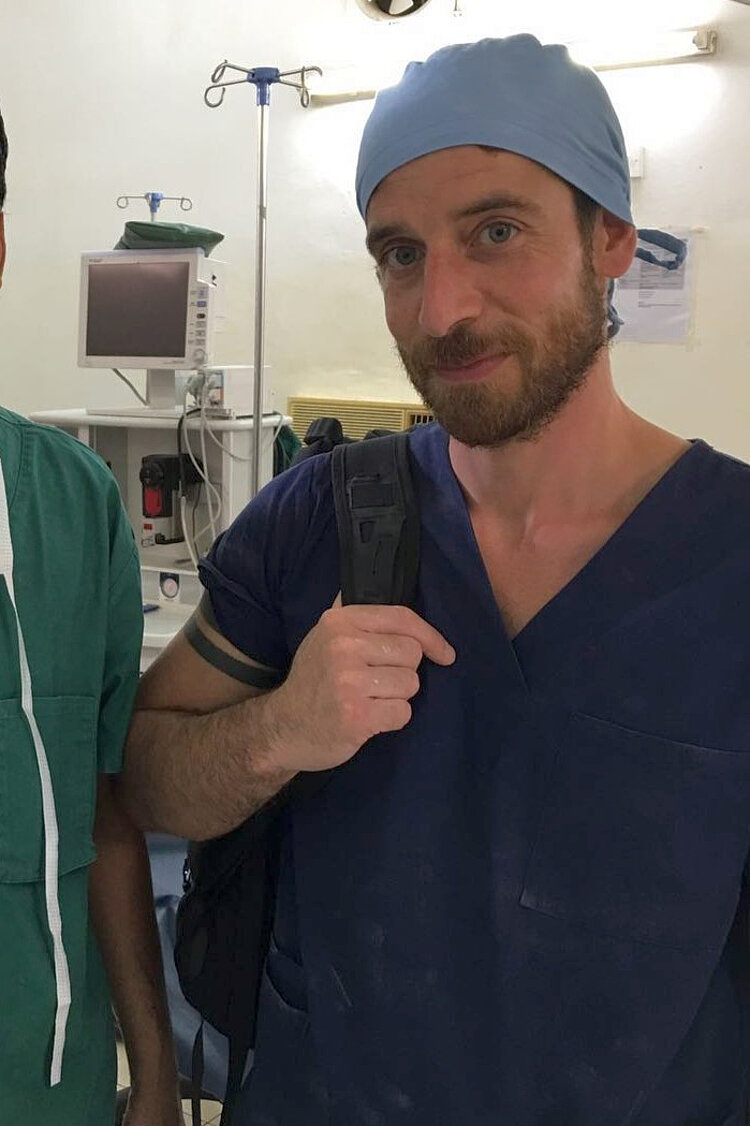 Ein Mann steht in OP-Kleidung steht in einem OP-Saal