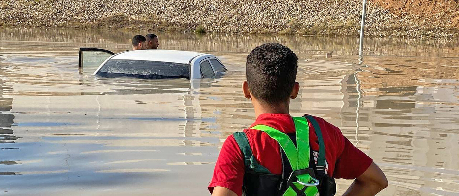 Menschen neben einem Auto im Hochwasser nach Unwetter in Libyen