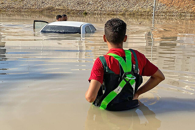 Menschen neben einem Auto im Hochwasser nach Unwetter in Libyen