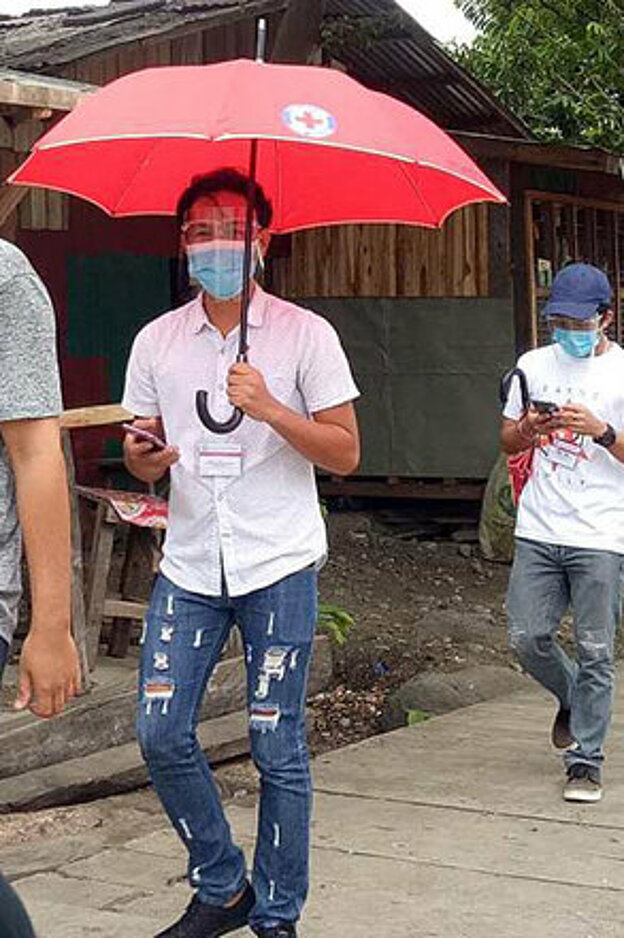 Philippinische Freiwillige laufen mit Rotkreuzregenschirmen 