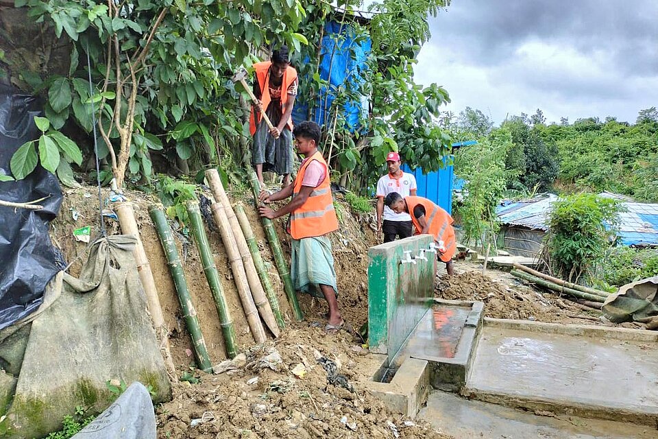 Arbeiter stabilisieren Hang mit Holzlatten
