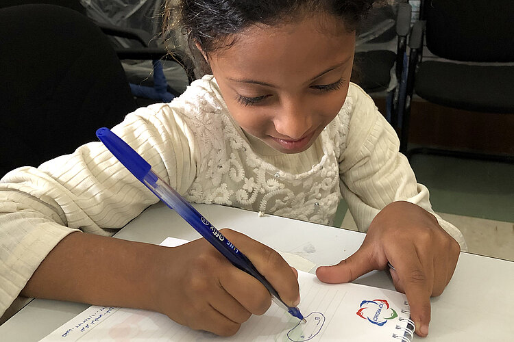 Kinderhilfe an Schulen im Jemen: Schulmädchen malt auf Schreibblock