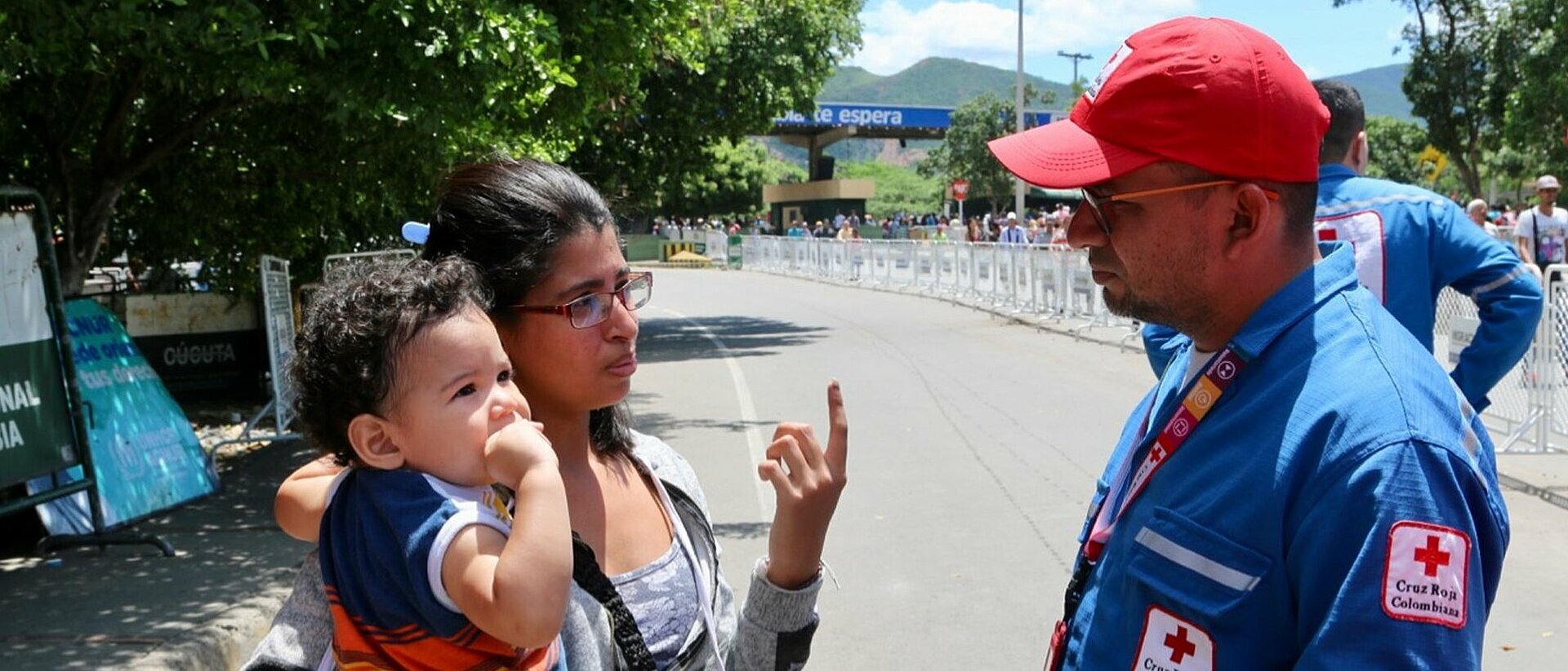 Frau mit Baby und Rotkreuz-Helfer an Migrationsroute nach Kolumbien