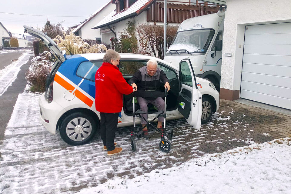 Ehrenamtliche hilft Senior aus einem PKW