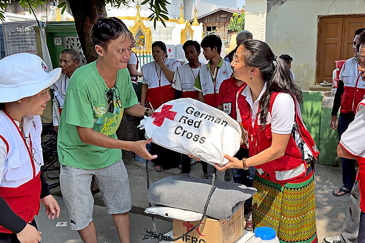 Helferin übergibt Hilfsgüter an Empfänger