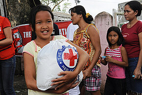 Philippinisches Mädchen hält eine Tüte mit Hilfsgütern