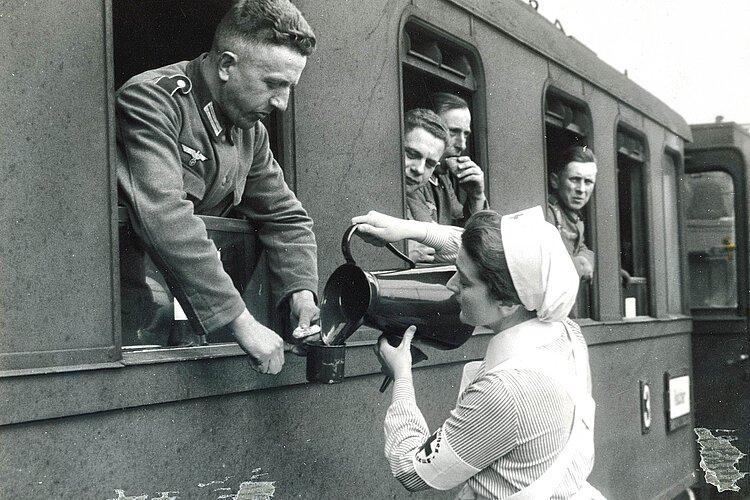 DRK-Helferin schenkt Soldaten im Zug Getränke ein