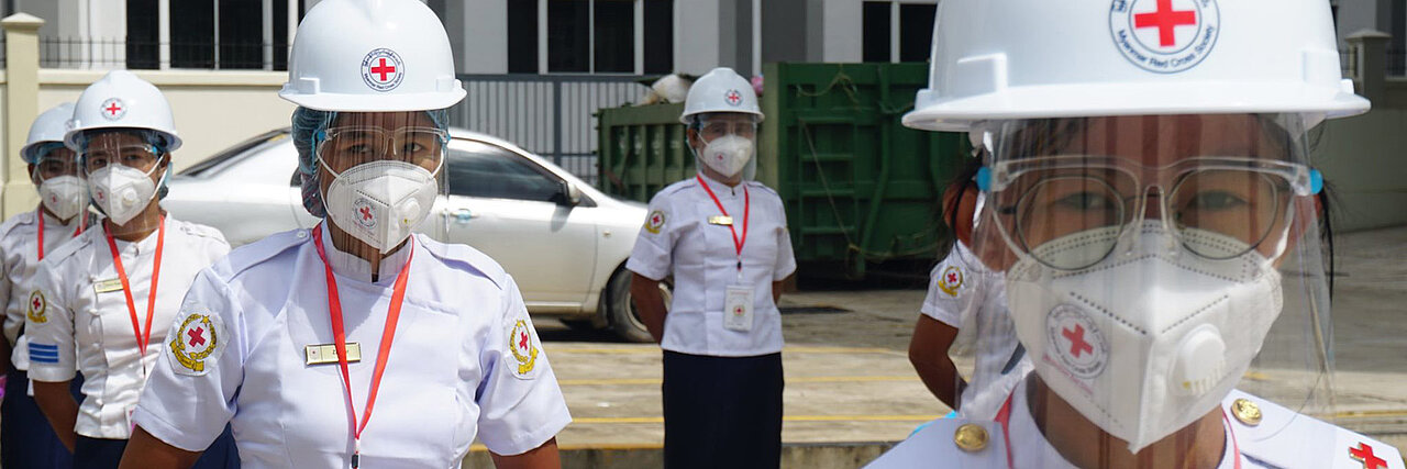 Freiwillige des Myanmarischen Roten Kreuzes in Uniform und Infektionsschutzausrüstung