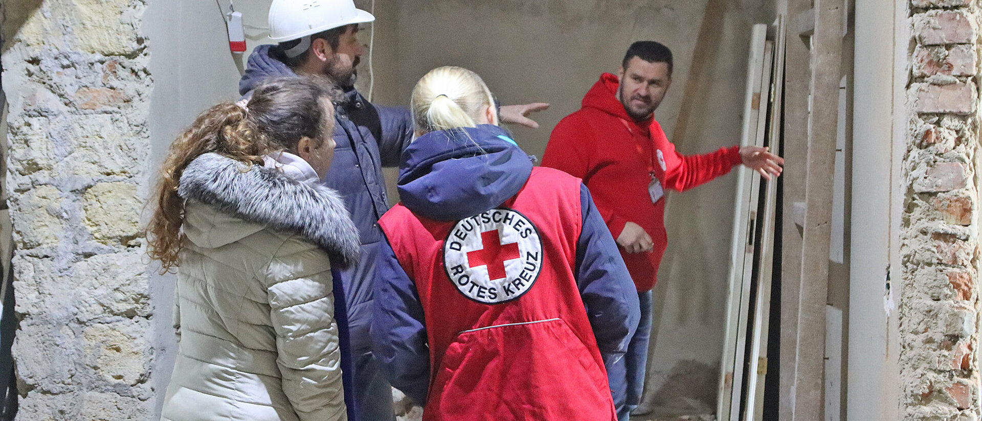 DRK-Helfer in der Ukraine vor einem zerstörtem Haus