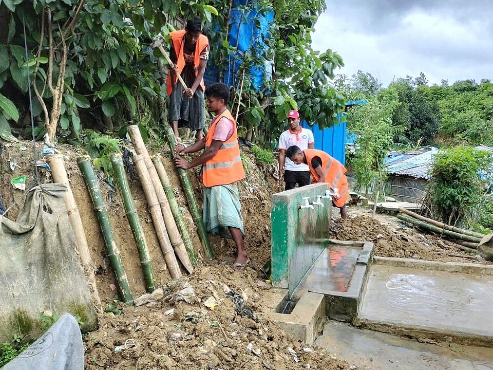 Mehrere Arbeiter stützen einen Hang mit Bambusstäben
