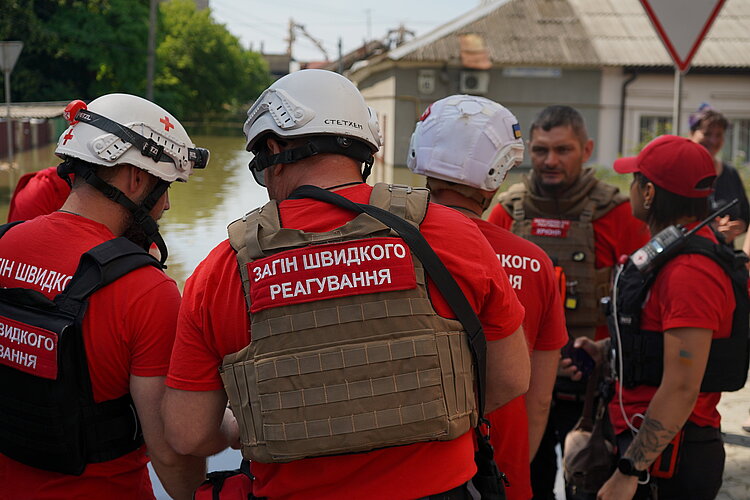 Helferinnen und Helfer vom Ukrainischen Roten Kreuz bei einer Teambesprechung im überfluteten Gebiet.