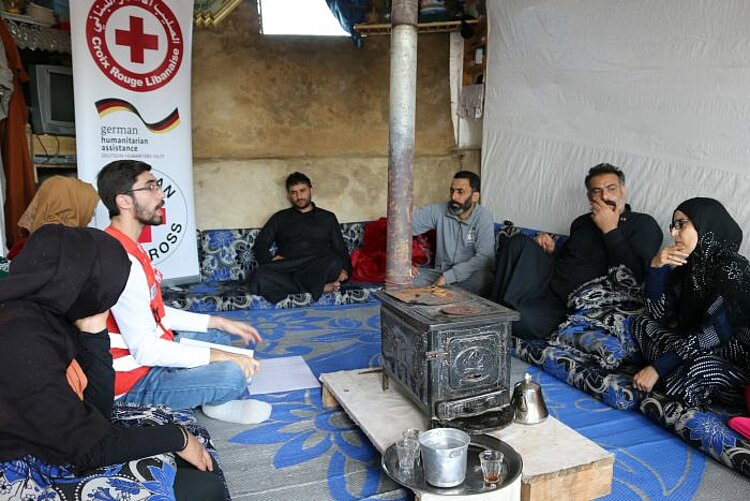 Mitarbeiter des Libanesischen Roten Kreuzes klärt Familie über Corona auf