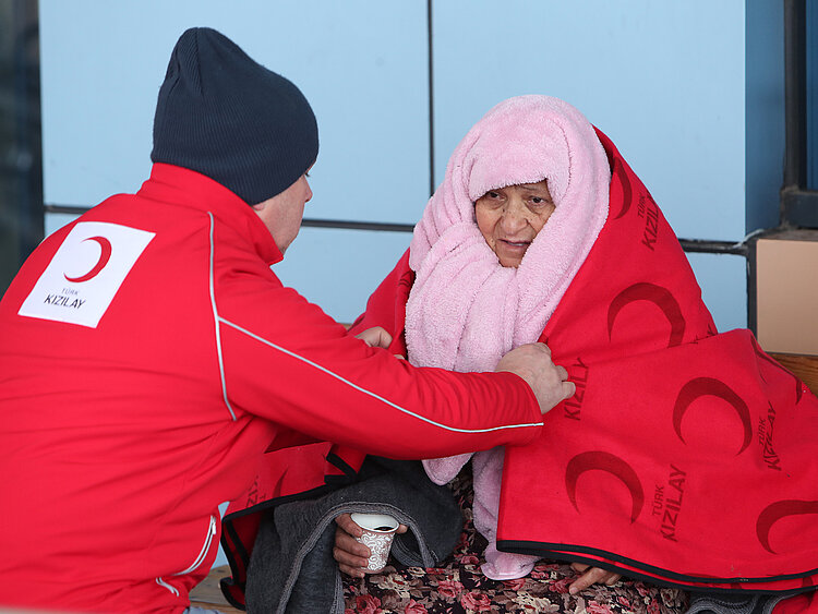 Helfer und Frau mit einer Decke nach dem Erdbeben, Türkei
