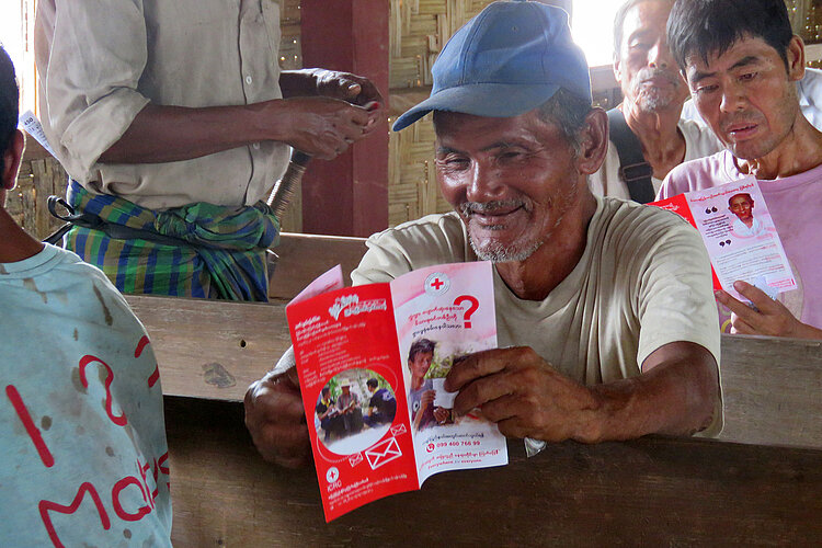 Zwei Männer in Myanmar lesen Rotkreuz-Flyer