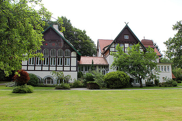 Fachwerkvilla auf einer Wiese mit Bäumen