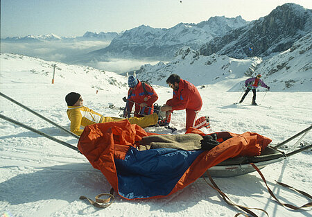 Vorbereitung eines verletzten Skifahrers für den Transport mit einem Akja in den 1990er Jahren (Michel Eram / DRK)