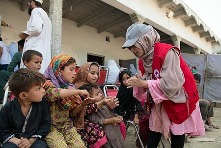 Kinder mit Rotkreuz-Helferin in Pakistan 