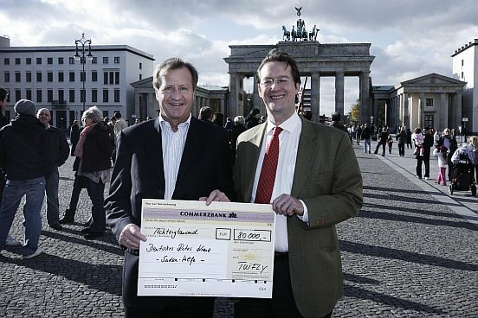 Foto:Friedrich Keppler (links im Bild), TUIfly-Geschäftsführer, überreicht einen symbolischen Scheck an DRK-Generalsekretär Clemens Graf von Waldburg-Zeil, im Hintergrund das Brandenburger Tor