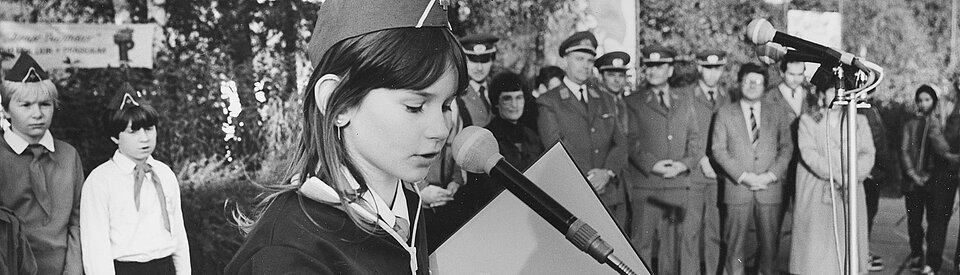Foto: JRK-lerin der DDR spricht auf einer Veranstaltung