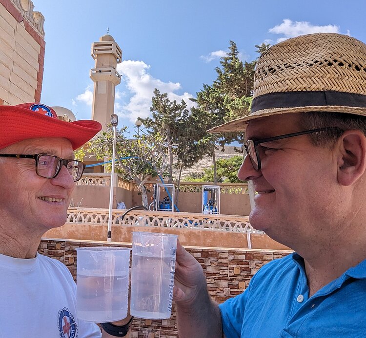 Zwei Männer vom DRK halten Wassergläswr in der Hand