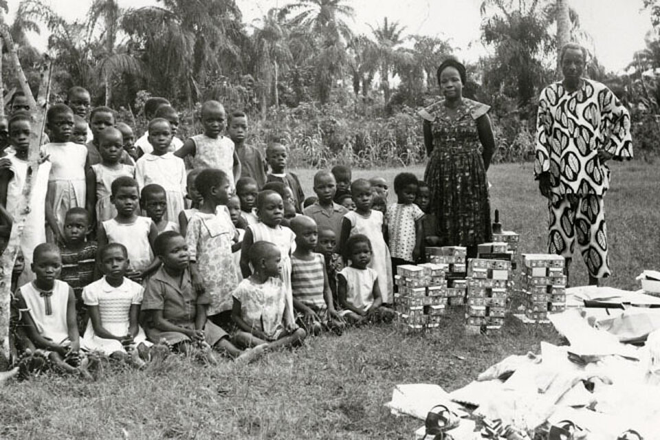 Foto: Eine Kindergruppe mit zwei Erwachsenen und Hilfsgütern