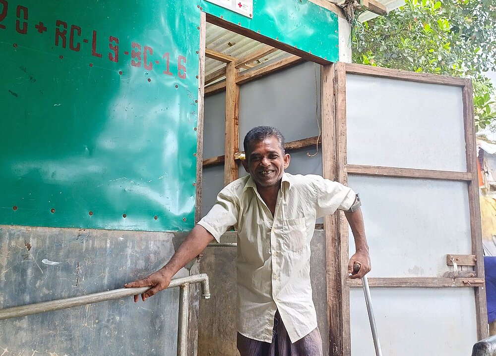 Mann vor Latrinenhütte