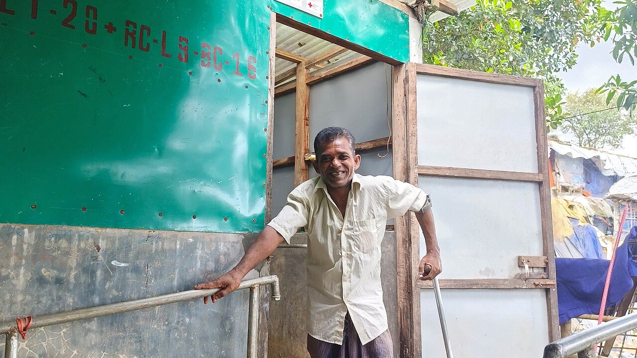 Mann vor Latrinenhütte