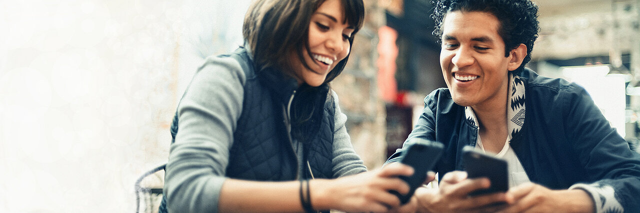 Foto: Mann und Frau im Gepräch - auch ihre Mobiltelefone schauend