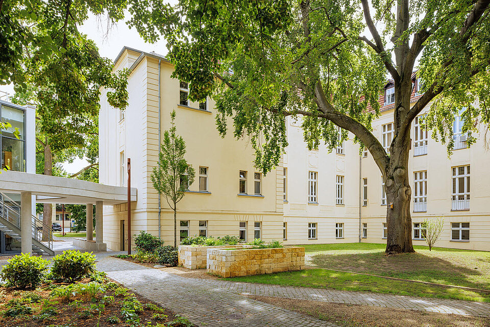 Gebäudeteile in Hof mit Bäumen