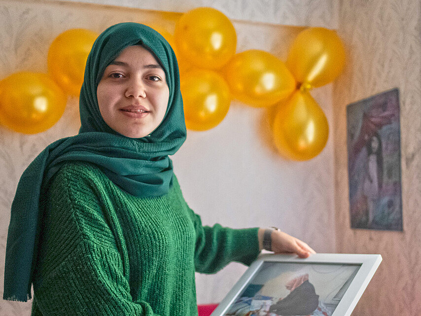 Junge Frau mit Kopftuch hält Foto