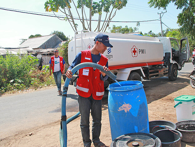 Red Cross volunteer in front of water truck