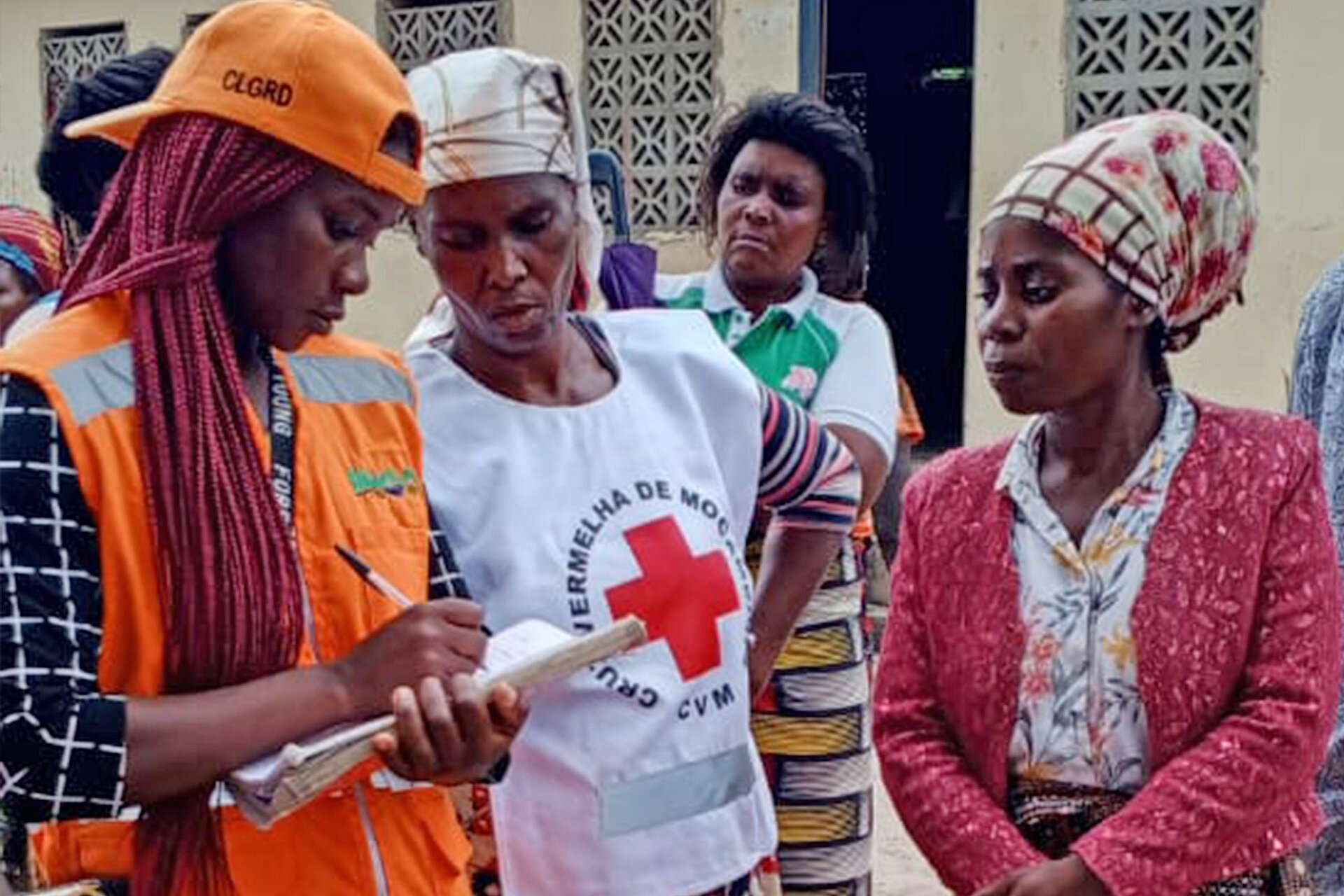 Helferin des Mosambikanischen Roten Kreuzes mit zwei Frauen 