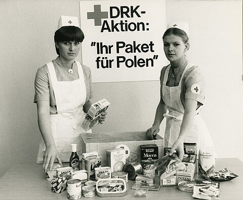 Deutsche Rotkreuzschwestern mit einem Standardpaket im Wert von fünfzig DM, das Lebensmittel und Hygieneartikel enthält (DRK)