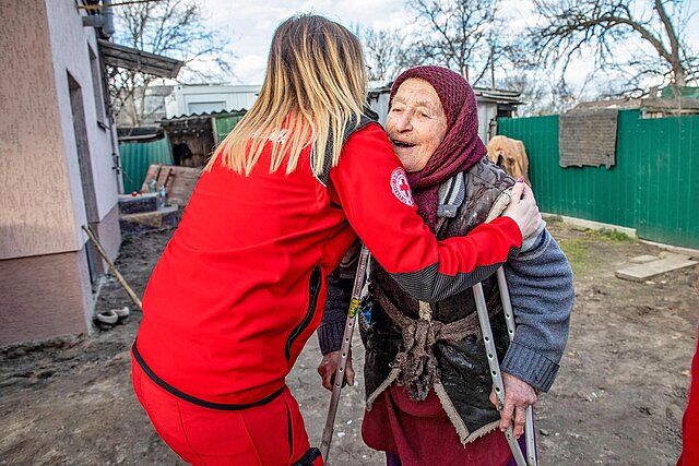 Rotkreuzlerin umarmt Seniorin