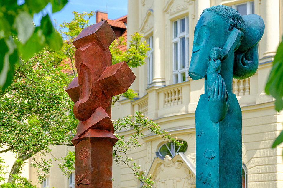 Eine rote und eine blaue Skultur vor einem Gebäude