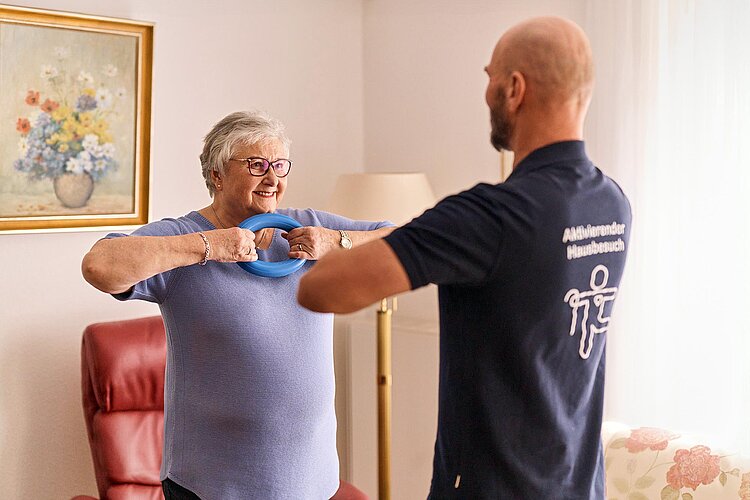 Seniorin und DRKler bei Gymnastik mit Ring