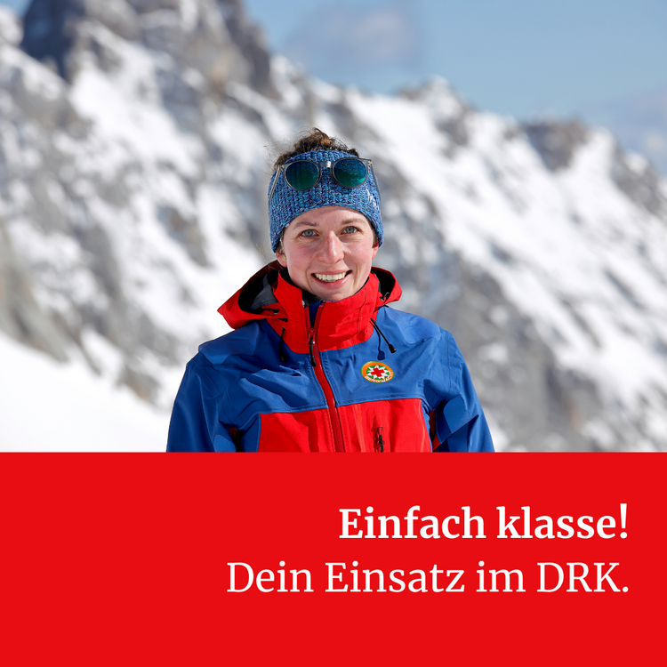 Eine Frau in blau-roter Jacke der Bergwacht und mit blauer Mütze steht vor einem verschneiten Berg. Darunter stht "Einfach klasse! Dein Einsatz im DRK."