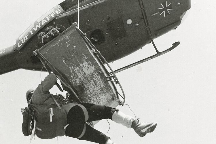 Ein Hubschrauber der Luftwaffe zieht eine Trage (Akja) mit einem Verletzten und dem Bergretter hoch (Archiv Bergecho / DRK)