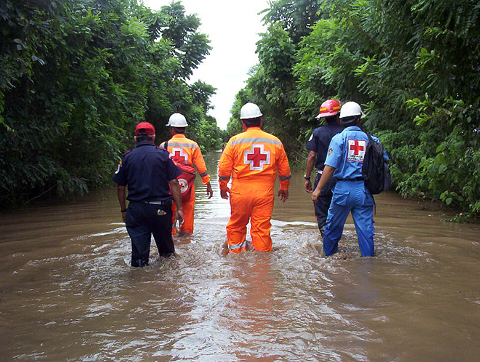 Rotkreuz-Helfer waten in einem Hochwassergebiet