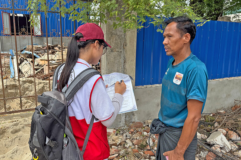 Freiwillige des Myanmarischen Rote Kreuzes spricht mit einem Mann, der vom Erdbeben betroffen ist